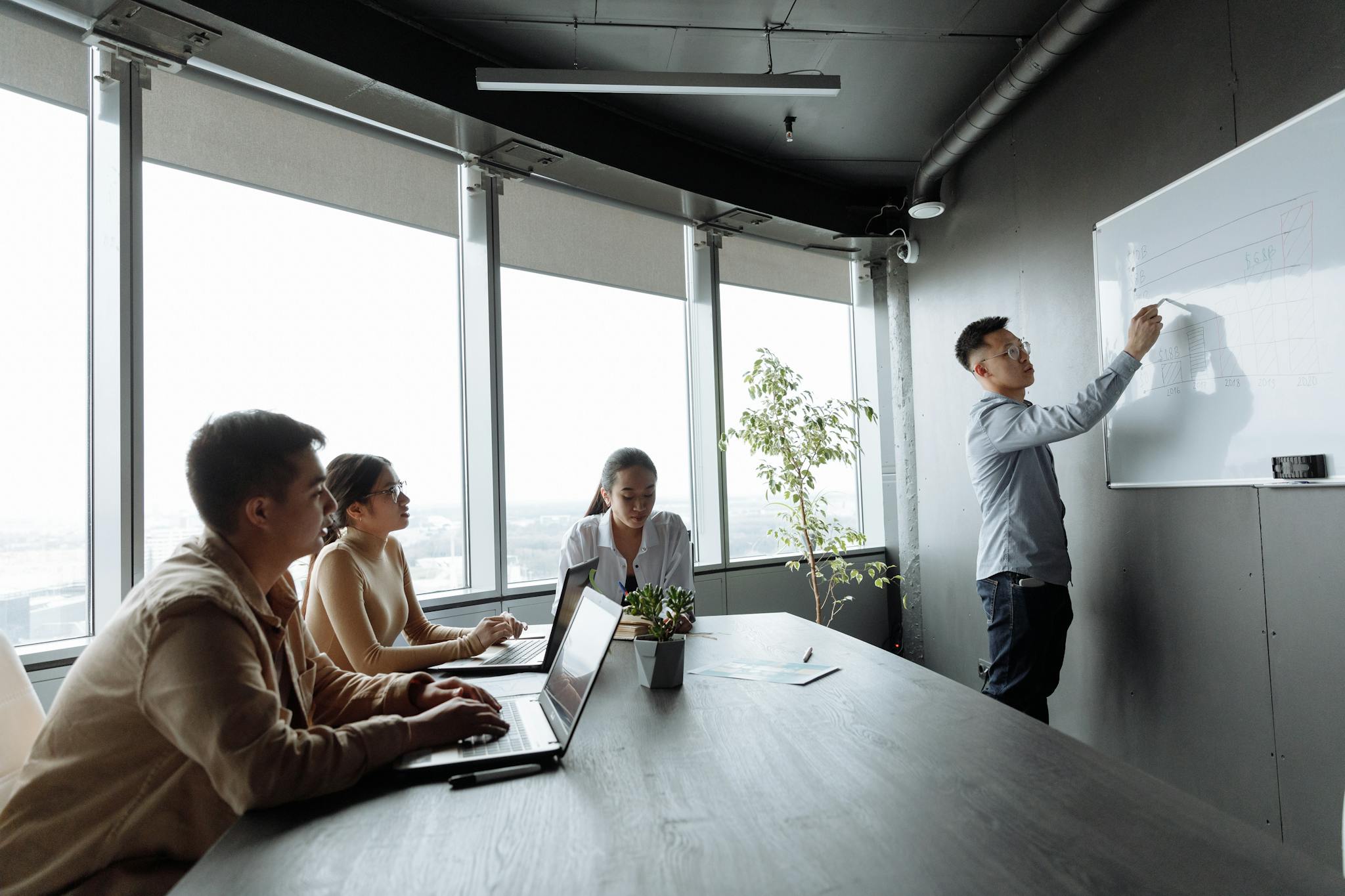 Photo by Thirdman Diverse coworkers engaged in a whiteboard presentation in a well-lit office.